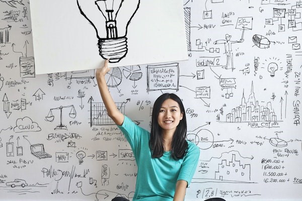 Woman holding up a light bulb drawing sign written narrative topics