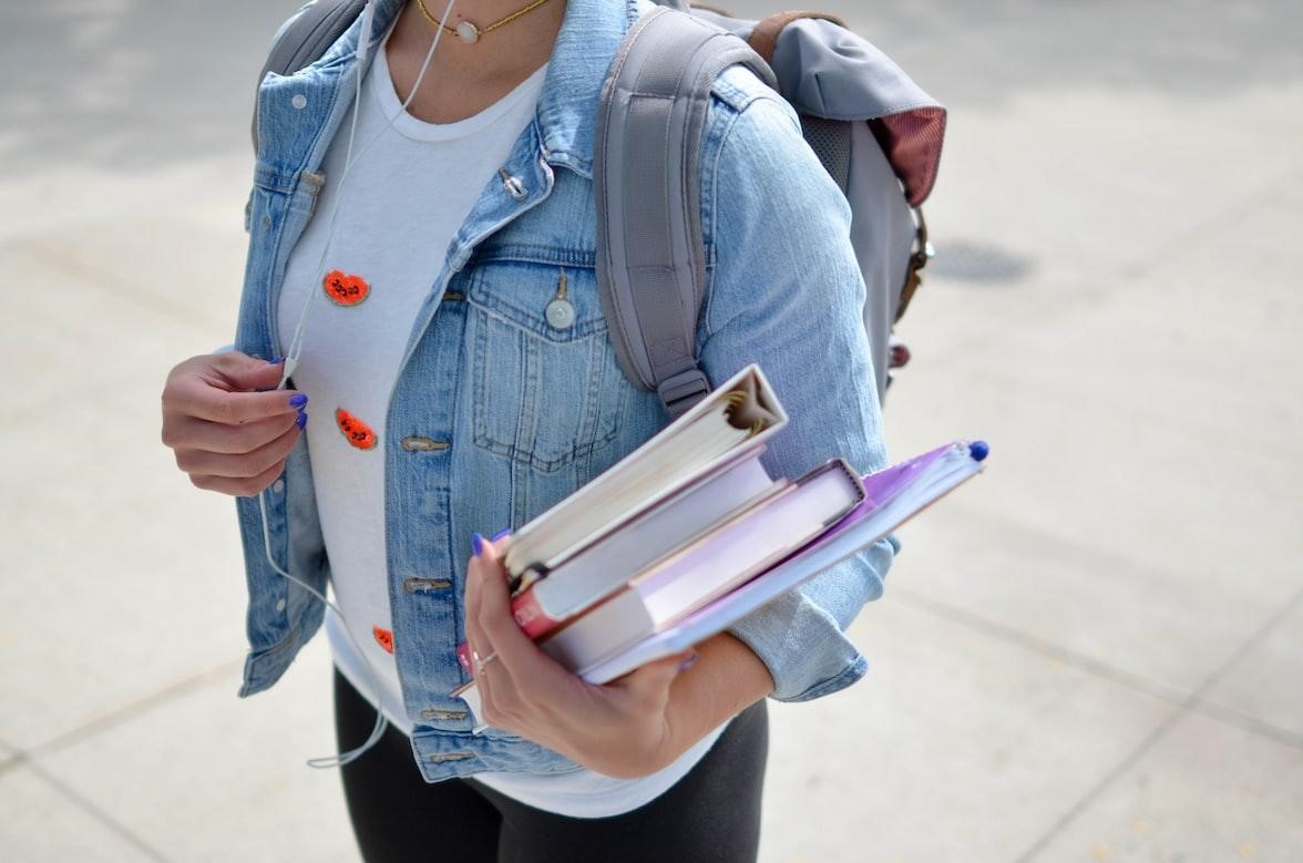 Female student standing outside holding a pile of books